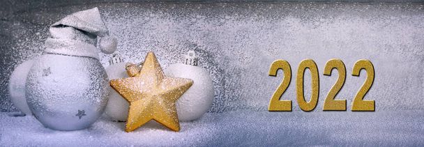 Золотой новый 2022 год рядом с рождественским декором, покрытым искусственным снегом  - Фото, изображение