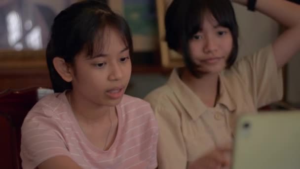 Twee Aziatische schattige meisjes genieten van chatten met vrienden met video-oproep op digitale tablet thuis. Moderne jonge levensstijl. Sociale online communicatie met live streaming op digitaal apparaat.  - Video
