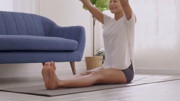 Morgens macht eine Asiatin Yoga, beugt sich nach vorne, geht von Kopf bis Knie, trainiert und trägt Sportbekleidung.. - Filmmaterial, Video