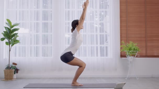 Em pé em Parsvakonasana postura, exercício de ângulo lateral, senhora asiática fazendo ioga, fêmea atraente em sportswear cinza, trabalhando em casa. - Filmagem, Vídeo