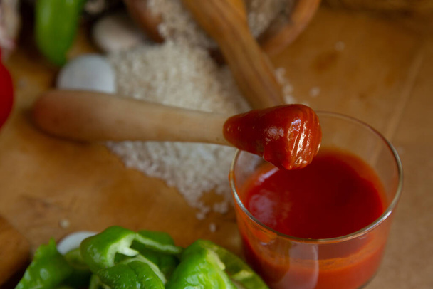Punainen paprika leikattu keittiöveitsellä ja jakaa tomaatti puulaudalla - Valokuva, kuva