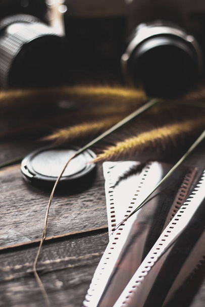 Cámara de película retro y película negativa sobre una mesa de madera negra - Foto, imagen