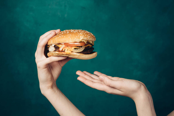 hamburger in hands close-up fast food green background - Φωτογραφία, εικόνα
