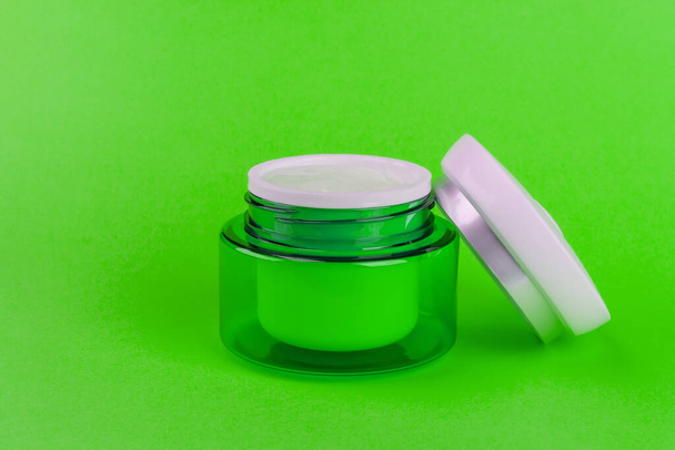 Green jar with a light day moisturizing hyaluronic cream gel for the face on a green background close-up - Фото, изображение