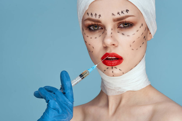 female patient posing in blue gloves red lips surgery facial rejuvenation close-up - Foto, afbeelding