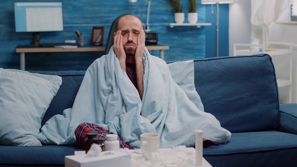 Kranker Mann mit Kopfschmerzen und Grippesymptomen blickt in Kamera - Foto, Bild