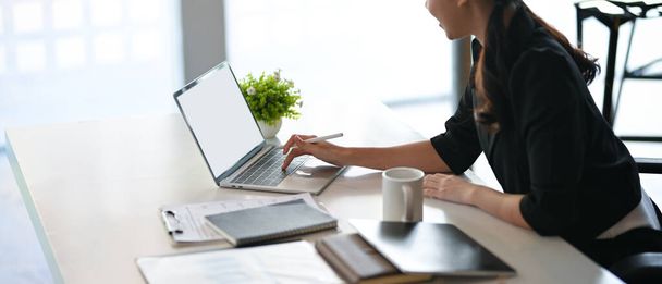 Recorte de mujer empresaria elegante trabajando y comprobando el objetivo de ventas a través de su computadora portátil en la oficina. - Foto, imagen