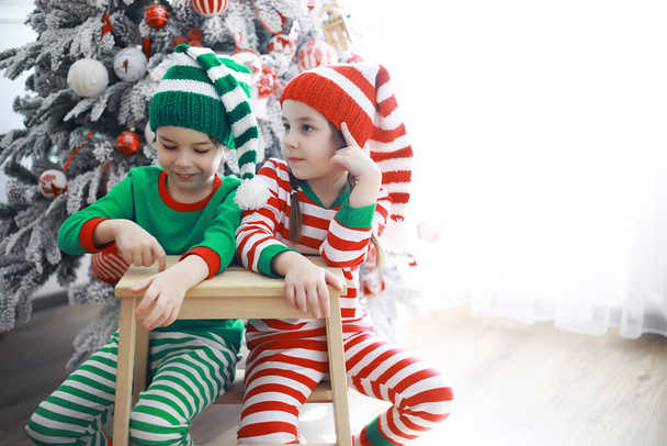 Los niños lindos en trajes de elfo de Navidad en una habitación bellamente decorada para la Navidad. Tiempo de milagros. Regalos de Santa Claus - Foto, Imagen