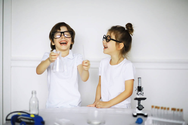 Deux enfants mignons à la leçon de chimie faisant des expériences isolées sur un backgroun blanc - Photo, image