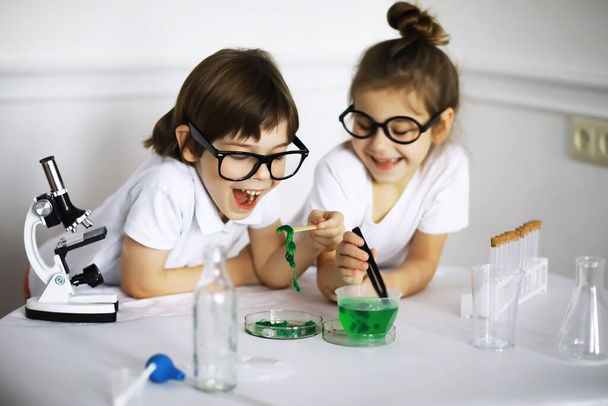 Dwoje uroczych dzieci na lekcjach chemii robi eksperymenty na białym tle - Zdjęcie, obraz