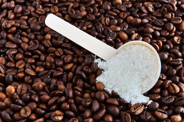 Sugar in a spoon and coffee sprinkled on the table. - Photo, Image