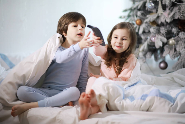 A family with children having fun on the bed under the covers during Christmas holidays. - Fotó, kép