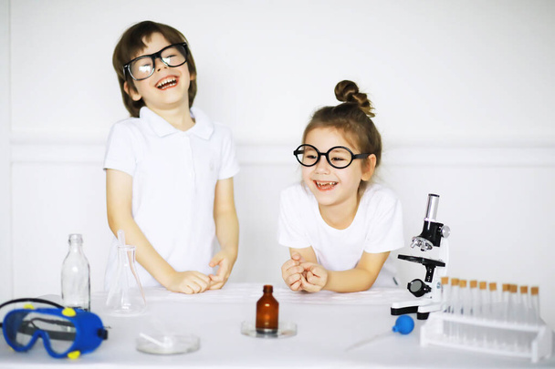 Dos niños lindos en la lección de química haciendo experimentos aislados en el fondo blanco - Foto, Imagen