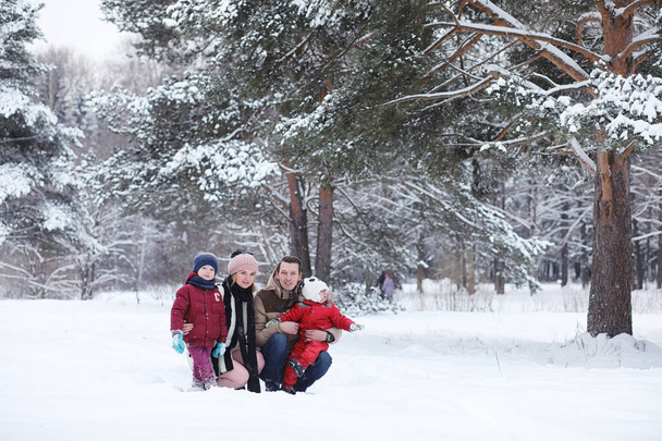 Młode rodziny z dziećmi są spacery w parku zimowym. Zimowy spacer rodziców z dziećmi. Chodzenie na weekend wakacje w zimie - Zdjęcie, obraz