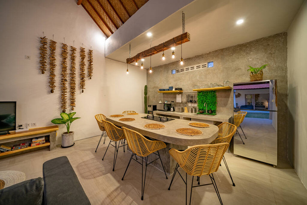 Canggu, Bali, Indonezja, 25 sierpnia 2019. nowoczesna kuchnia z urządzeniami. Subtelne oświetlenie. stół jadalny z polerowanego betonu. - Zdjęcie, obraz