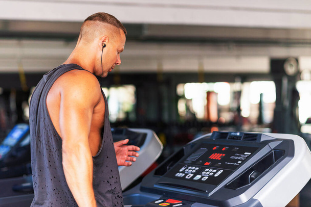 Young man in sportswear running on treadmill at gym.Handsome sport gym man running on the treadmill.Indoors shot.Man running in a gym on a treadmill.Exercising fitness.Healthy lifestyle concept. - Photo, Image