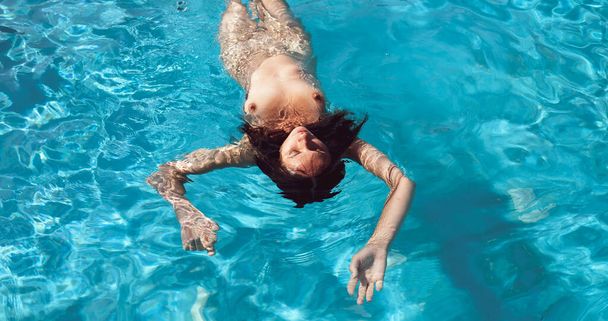 Naked woman outdoors. Beautiful young nude woman in swimming pool. - Foto, Imagem