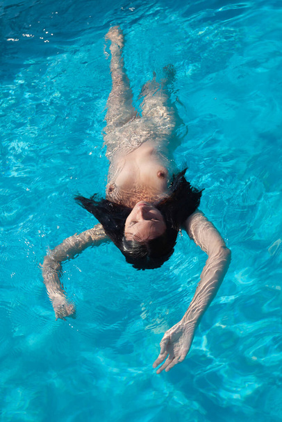 Naked woman outdoors. Beautiful young nude woman in swimming pool. - Foto, Bild