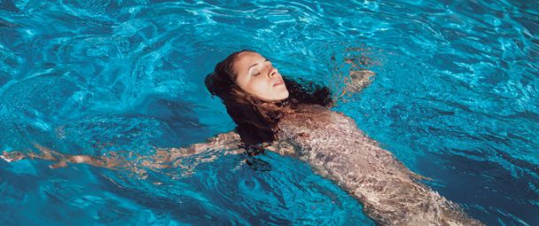 Naked woman outdoors. Beautiful young nude woman in swimming pool. - 写真・画像