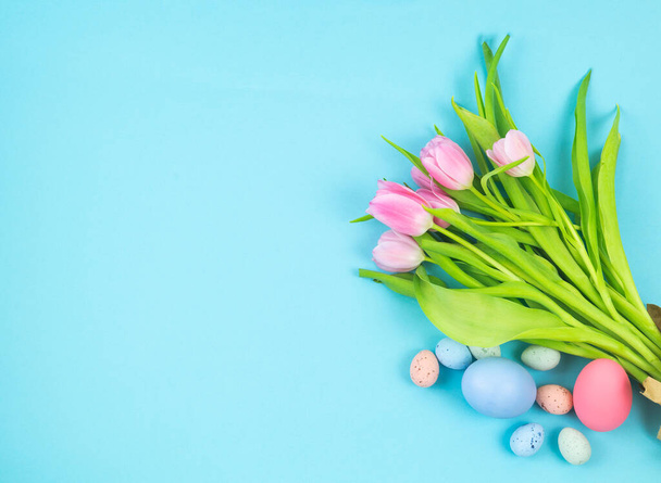 Bouquet of tulips and Easter eggs on a blue background Copy space on the left. Concept of spring. - Photo, Image