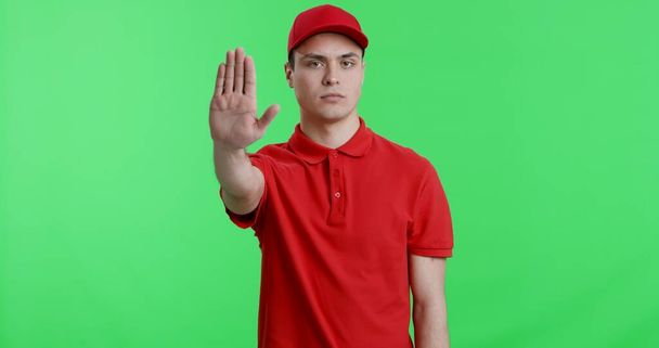 Doručovatel v červené uniformě gestikuluje stop sign na kameru - Fotografie, Obrázek