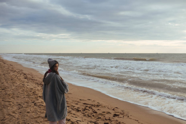 Молодая женщина на холодном осеннем побережье позирует перед камерой - Фото, изображение