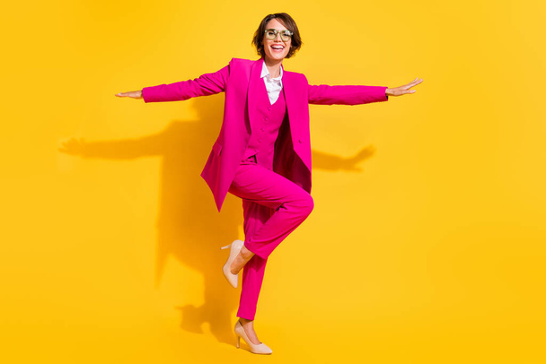 Фото забавной милой молодой женщины в розовых очках в костюмах, танцующей на изолированном желтом фоне - Фото, изображение