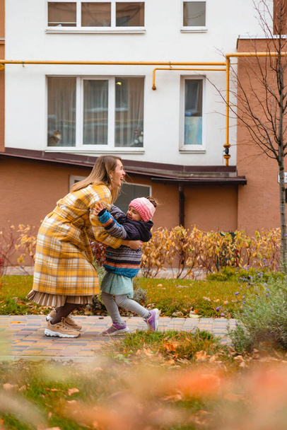 Mother playing with daughter on autumn street. Fall colors - Fotografie, Obrázek