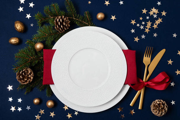Feestelijke kersttafel met gouden bestek en porseleinen bord en kerstversiering. Mockup voor plaatskaart, diner uitnodiging, restaurant menu sjabloon. Kopieerruimte - Foto, afbeelding