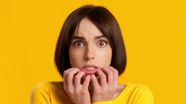 Ansiosa joven mujer preocupante que sufre de ansiedad sobre fondo amarillo - Imágenes, Vídeo