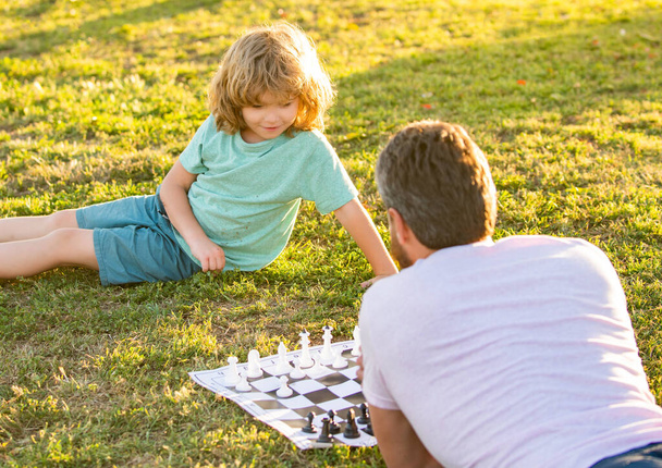 papá y el niño juegan juego de lógica. padre e hijo jugando ajedrez en la hierba. Día de los padres. familia feliz. - Foto, imagen