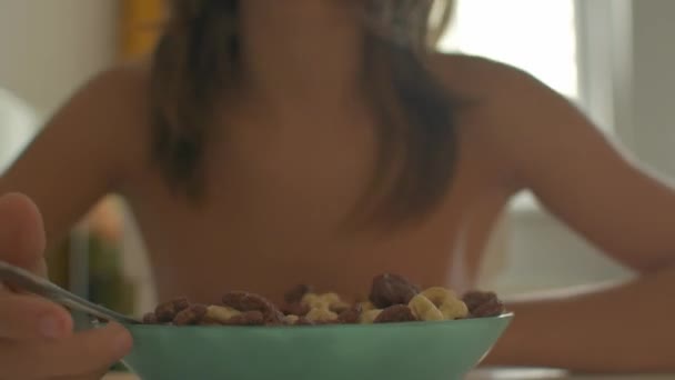 Gros plan jeune garçon à table manger des céréales petit déjeuner à l'intérieur avec des gestes de main mans dans le cadre - Séquence, vidéo