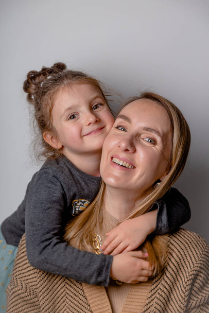 Retrato de mãe feliz e bonita com sua filha no fundo cinza mínimo. - Foto, Imagem