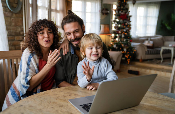 Happy family with kid having fun using laptop together, watching internet video, making online call at home - 写真・画像