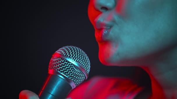 Profi énekes. Fiatal izgatott felismerhetetlen nő énekel mikrofonba, a neon fények, oldalnézet - Felvétel, videó