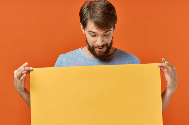 Emotionaler Mann mit einem gelben Banner Design orange Hintergrund - Foto, Bild