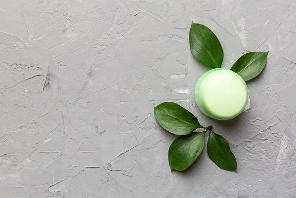 Produtos cosméticos orgânicos com folhas verdes no fundo de cimento. Espaço de cópia, flat lay. - Foto, Imagem