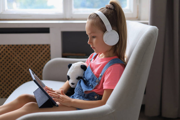 Дистанційне навчання. Весела маленька дівчинка використовує ноутбук комп'ютер, який навчається через онлайн систему електронного навчання
 - Фото, зображення