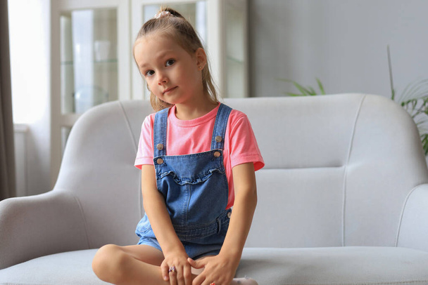 Excited child looking at camera while sitting in living room at home - Photo, image