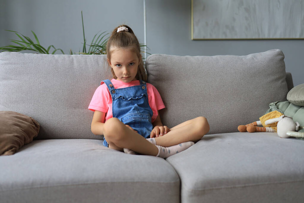 Sad little girl sitting on sofa alone at home - Foto, Bild