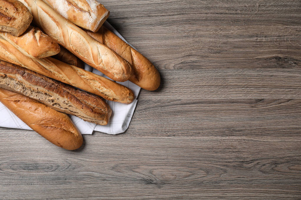 Different tasty baguettes on wooden table, flat lay. Space for text - Foto, afbeelding