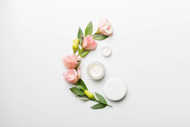 Composition with cosmetic products and beautiful roses on white background. Copy space, flat lay. - Foto, Imagen