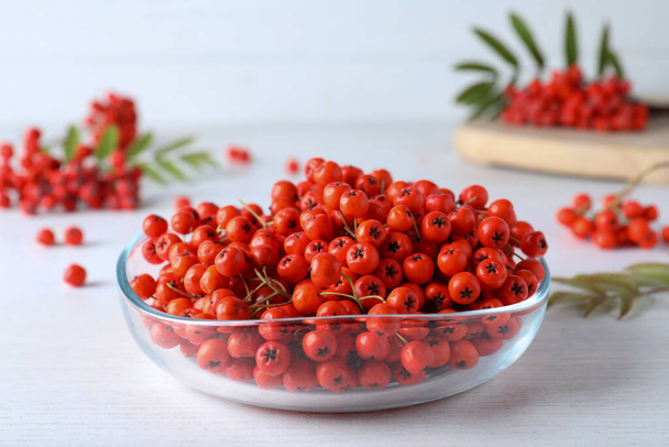 Fresh ripe rowan berries in glass bowl on white wooden table - Foto, afbeelding