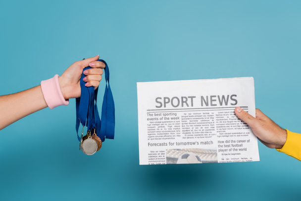 cropped view of man holding newspaper near woman with medals on blue - Photo, Image