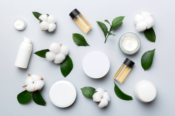 Organic cosmetic products with cotton flower and green leaves on wooden background. Flat lay. - Photo, Image