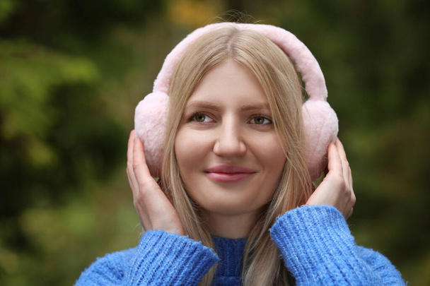 Νεαρή όμορφη γυναίκα φοράει ζεστά ακουστικά σε εξωτερικούς χώρους - Φωτογραφία, εικόνα