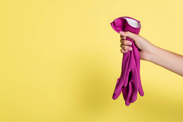 cropped view of woman holding pink rubber gloves on yellow  - Фото, зображення