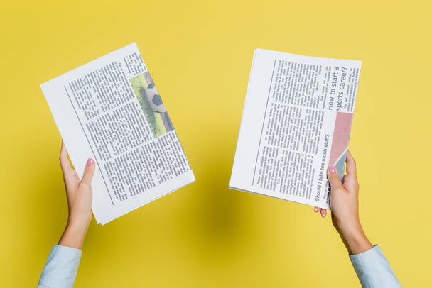 cropped view of woman holding newspapers on yellow - Foto, Imagem