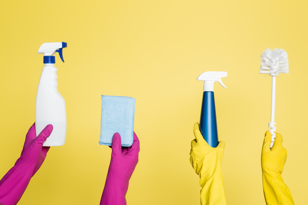 bijgesneden weergave van reinigers met spuitflessen met wasmiddel, vod en toiletborstel geïsoleerd op geel - Foto, afbeelding