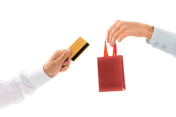 oříznutý pohled na ženu držící nákupní tašku poblíž mužské ruky s kreditní kartou izolovanou na bílém  - Fotografie, Obrázek